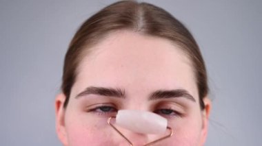 Bir kadının yakın plan portresi alnındaki kırışıklıkları düzeltmek için kuvars silindirli masaj aleti kullanıyor.