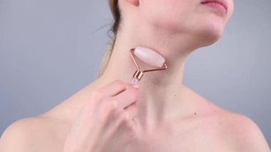 Boynundaki kırışıklıklara karşı alternatif bir dövüş için kuvars silindirli masaj aleti kullanan bir kadının yakın plan portresi. Venüs 'ün halkalarının yumuşaklığı