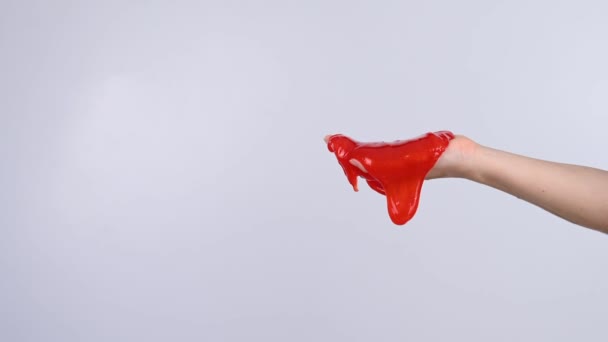 红色的黏液从一个女人的手上滑落在白色的背景上 — 图库视频影像