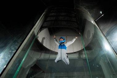 Bir kadın rüzgar tünelinde uçuyor. Serbest düşüş simülatörü
