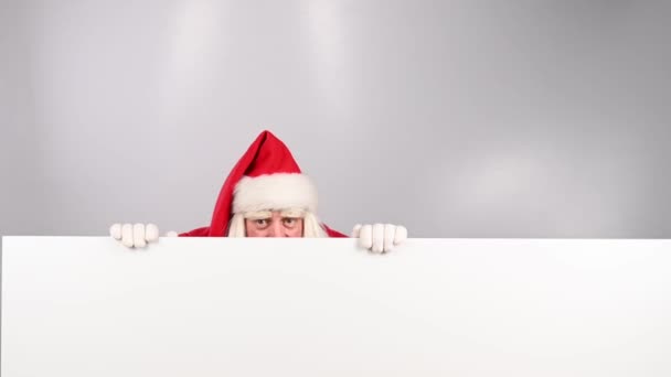 Hinter Einer Werbung Auf Weißem Hintergrund Lugt Der Weihnachtsmann Hervor — Stockvideo