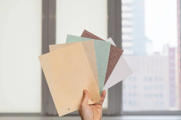 stock image Woman holding fabric samples of roller blinds against window background