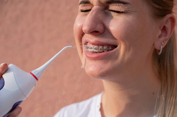 Uma Mulher Com Aparelho Nos Dentes Usa Irrigador Retrato Close — Fotografia de Stock