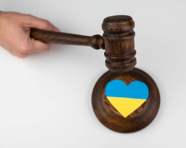 Beyaz arka planda Ukrayna bayrağıyla hakimlere vuran kadın.