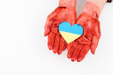 Elleri kana bulanmış bir kadın beyaz arka planda Ukrayna bayrağı taşıyan bir kalp tutuyor.