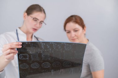 Kadın doktor, kadın hastaya iç organların MRI 'sını açıklıyor.