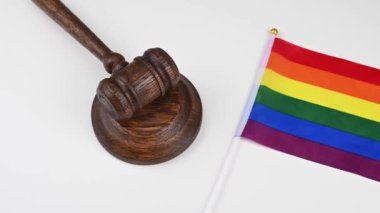 Hakim beyaz bir masada el bilgisayarı olan Igbt bayrağının yanındaki tokmağı döver.