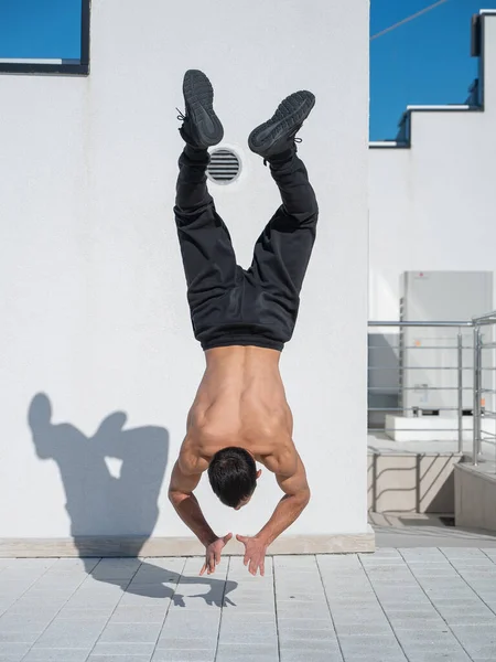 Mand Gør Håndstand Udendørs Mod Hvid Væg - Stock-foto