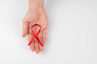 Beyaz arka planda kırmızı kurdeleli bir kadın avucu. AIDS 'le mücadelenin sembolü. Boşluğu kopyala