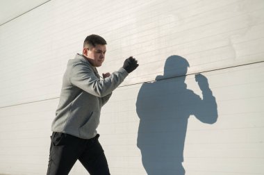 Kapüşonlu beyaz adam dışarıda boks antrenmanı yapıyor.