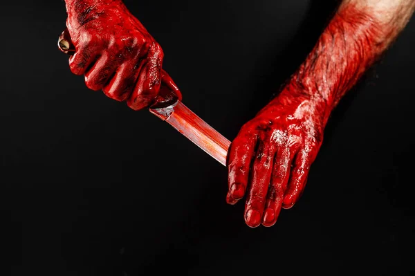 一个人在黑色的背景上用手擦拭一把血淋淋的刀 — 图库照片