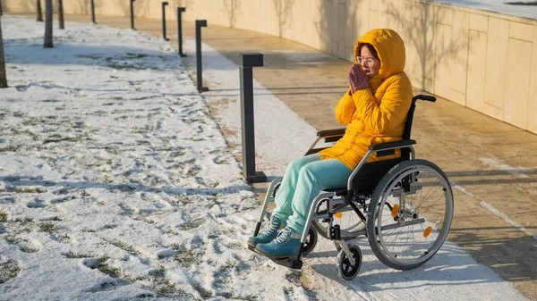 坐在轮椅上的女人在冬天的公园里感冒了 — 图库照片