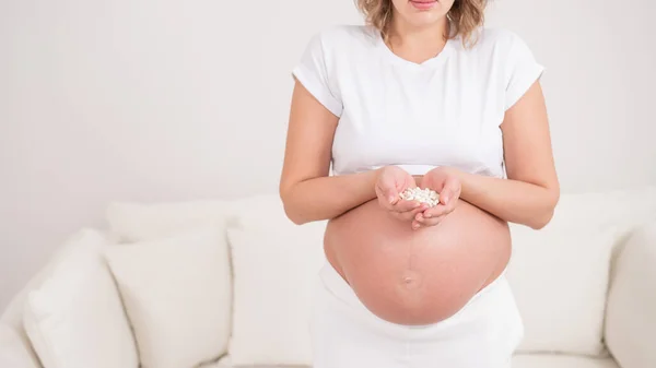 Een Gezichtloze Zwangere Vrouw Houdt Een Handvol Witte Pillen Vast — Stockfoto