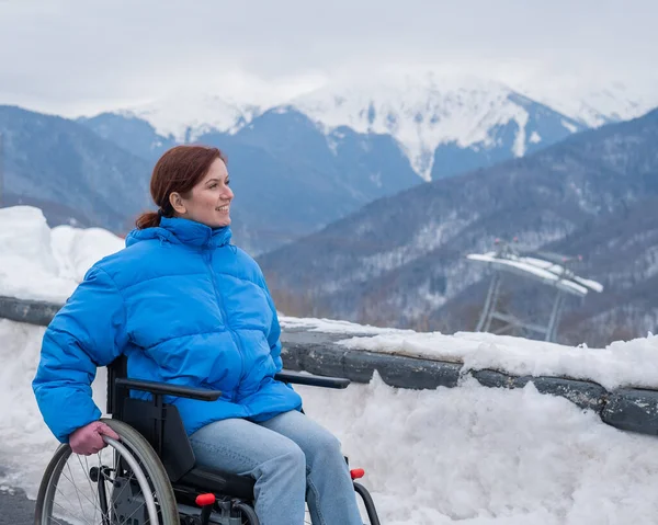 Caucasian woman in a wheelchair travels in the mountains in winter
