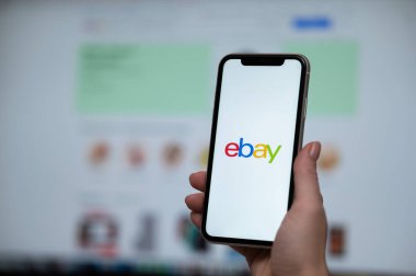 3 Aralık 2022, Almaty, Kazakistan: Bir kadın bilgisayarın arka planında ebay uygulaması olan bir akıllı telefon tutuyor.