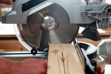 Usta atölyede dairesel testere ile tahtayı keser.