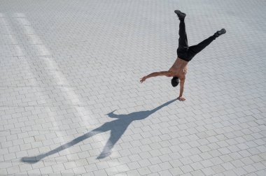 Tişörtsüz bir adam dışarıda elini kolunu sallayarak yürüyor. Yukarıdan görüntüle