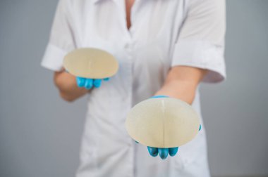 Doktor plastik cerrah farklı göğüs implantları gösteriyor.