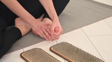 Beyaz kadın sadhu çivileri üzerinde durduktan sonra yoga minderine oturur.