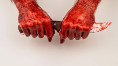 Yüzü olmayan bir adam bıçağı bıçağından tutar. Beyaz arka planda kana bulanmış erkek eller.