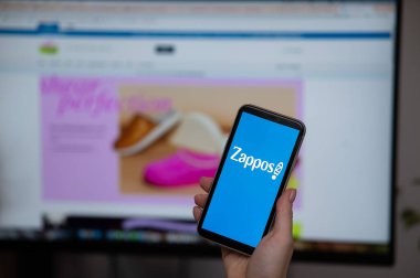 3 Aralık 2022 Almaty Kazakistan: Zappos logosu olan yüzsüz kadın ekranda arkaplanda akıllı telefon tutuyor