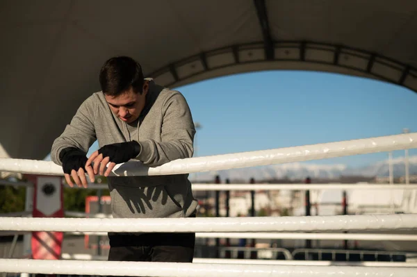 Caucasian male boxer resting in the ring outdoors