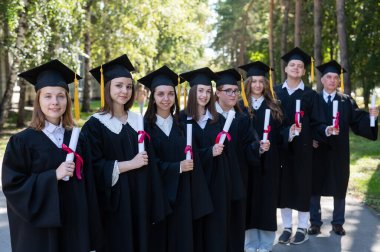 Mezuniyet elbisesi giymiş bir sürü genç dışarıda bekliyor. Yaş öğrencisi