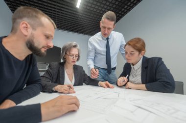 Patron ofis konferans odasında üç çalışana talimat verir. Beyin fırtınası yapan mühendisler ve mimarlar.