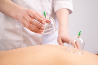 Kadın masaj terapisti hastaların sırtında süpürge kullanıyor.