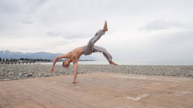 Çakıl taşlı plajda ters takla atan beyaz bir adam.