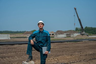 İnşaat alanında elinde dizüstü bilgisayar tutan beyaz erkek müteahhit.