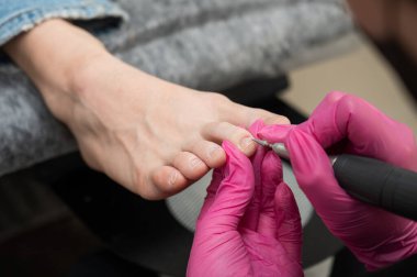 Usta müşteriye donanım pedikürü yapıyor. Kütikül tedavisi