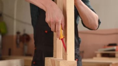 Bir marangoz ahşap kalasları ölçer ve atölyede bir kalemle izler bırakır.