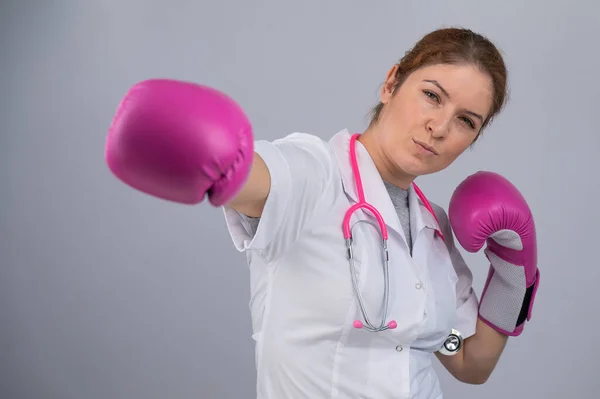 Woman doctor in pink boxing gloves on a white background