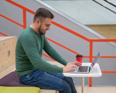 Ortak çalışma alanında dizüstü bilgisayarda çalışan beyaz bir adam. Boşluk aç