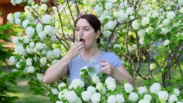 Biała Kobieta Bierze Lek Przeciwhistaminowy Wyjmuje Szpilkę Nosa Pobliżu Kwitnącego — Wideo stockowe