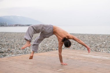 Çakıl taşlı plajda ters takla atan beyaz bir adam.
