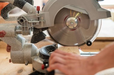 Usta atölyede dairesel testere ile tahtayı keser.