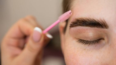 Yakın plan beyaz kadın kaşlarını tarıyor.