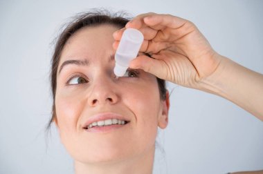 Beyaz kadın gözlerine nemlendirici damlalar damlatıyor