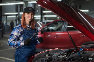 Tulumlu bir kadın tamirci araba tamir ediyor.