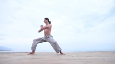 Kafkasyalı, uzun saçlı, dışarıda qigong antrenmanı yapan bir adam.