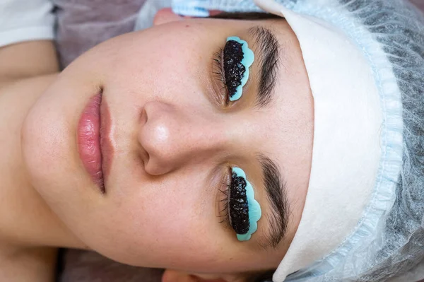 Close-up portrait of a woman on the procedure of lamination and tinting of eyelashes. Permanent makeup