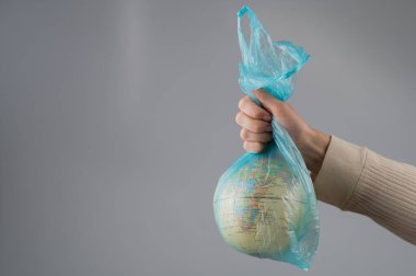 Beyaz arka planda plastik bir torba içinde bir kadın elinde bir küre tutuyor.
