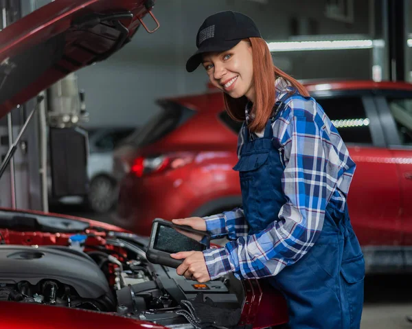 Caucasian female auto mechanic uses a special computer to diagnose faults