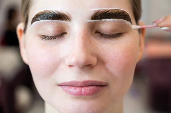 The master paints the eyebrows of a woman