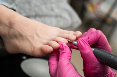 Usta müşteriye donanım pedikürü yapıyor. Kütikül tedavisi