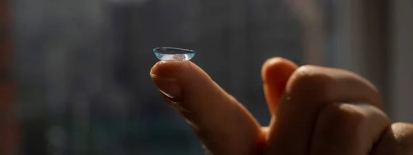 Close-up of a contact lens on a womans index finger