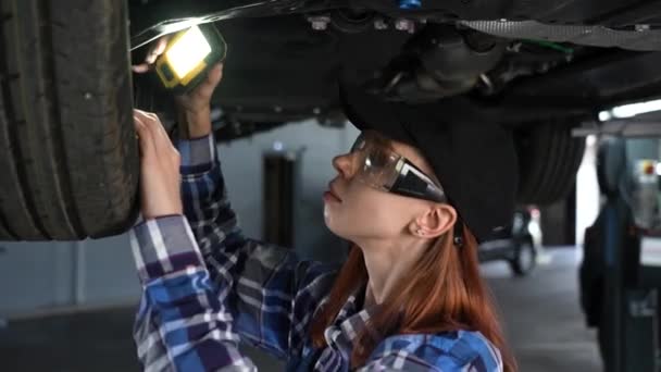 Uma Mecânica Feminina Inspeciona Carro Levantado Uma Rapariga Num Trabalho — Vídeo de Stock