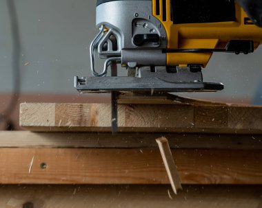 Atölyede elektrikli bir yapbozla tahta kesen bir adamın yakın çekimi.